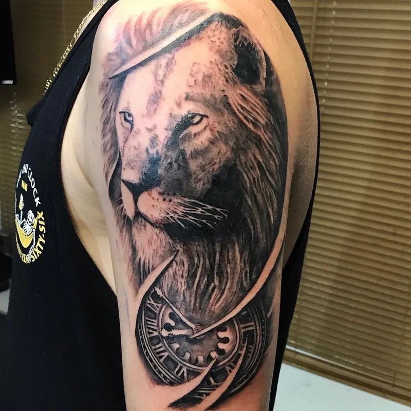 Black and grey realism tattoo on the shoulder of a lion's portrait, with a pocket watch and a torn-skin design effect below.