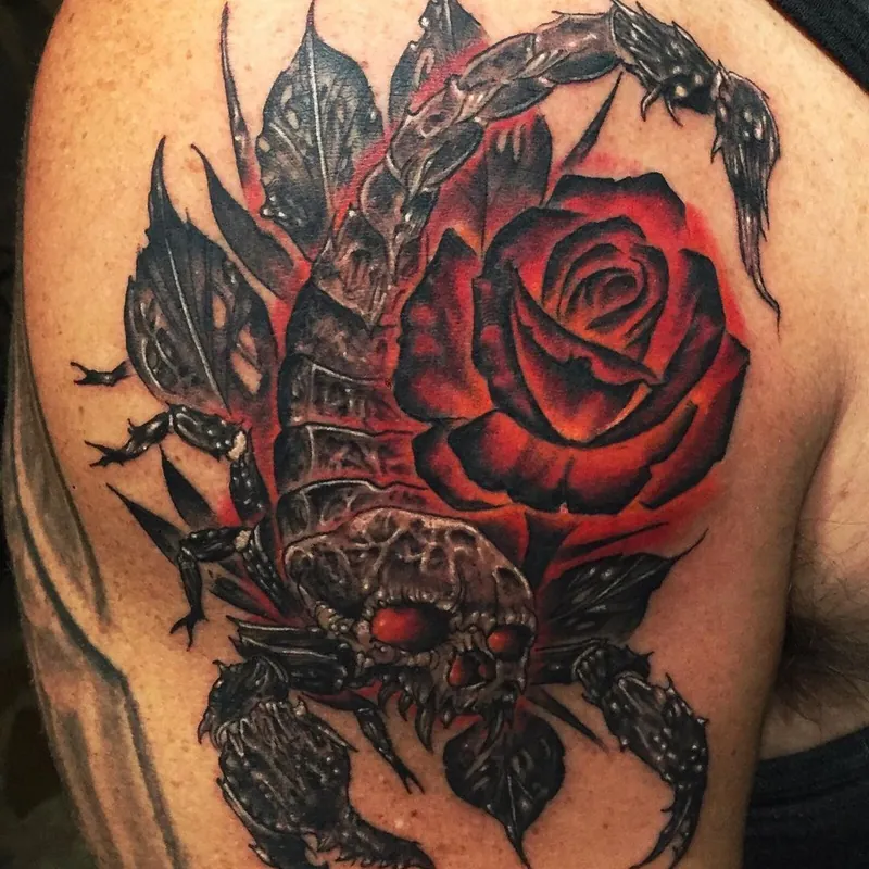 Tattoo on the shoulder of a dark scorpion with a skull-textured body, gripping a red rose against a red glow background.