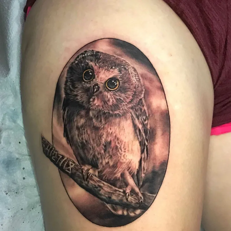 Black and grey realism tattoo of a baby owl perched on a branch inside an oval frame on the thigh, with a memorial date inked into the wood.