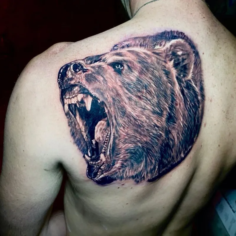 Black and grey realism tattoo of a roaring grizzly bear head, covering the shoulder blade.