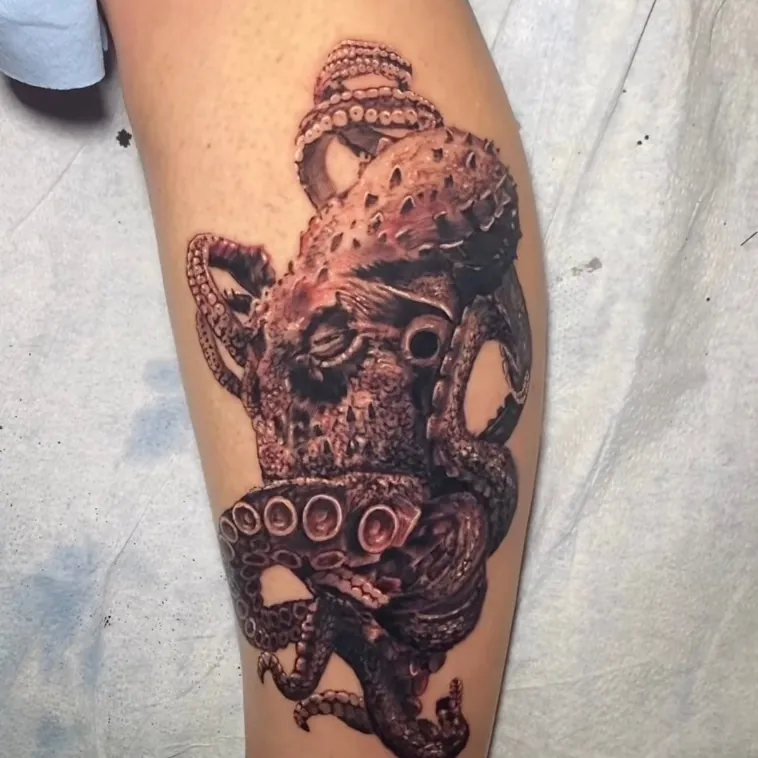 Black and grey realism tattoo of a highly detailed octopus head with suckered tentacles wrapping around the leg.