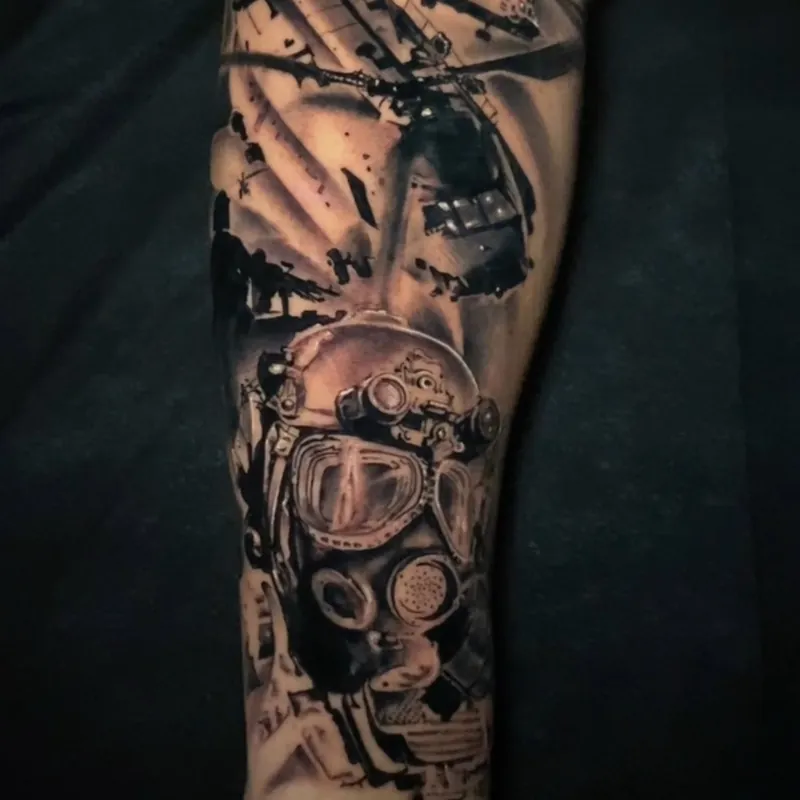 Black and grey realism tattoo of a military helicopter above a soldier's helmet fitted with goggles and a mask, covering the arm.