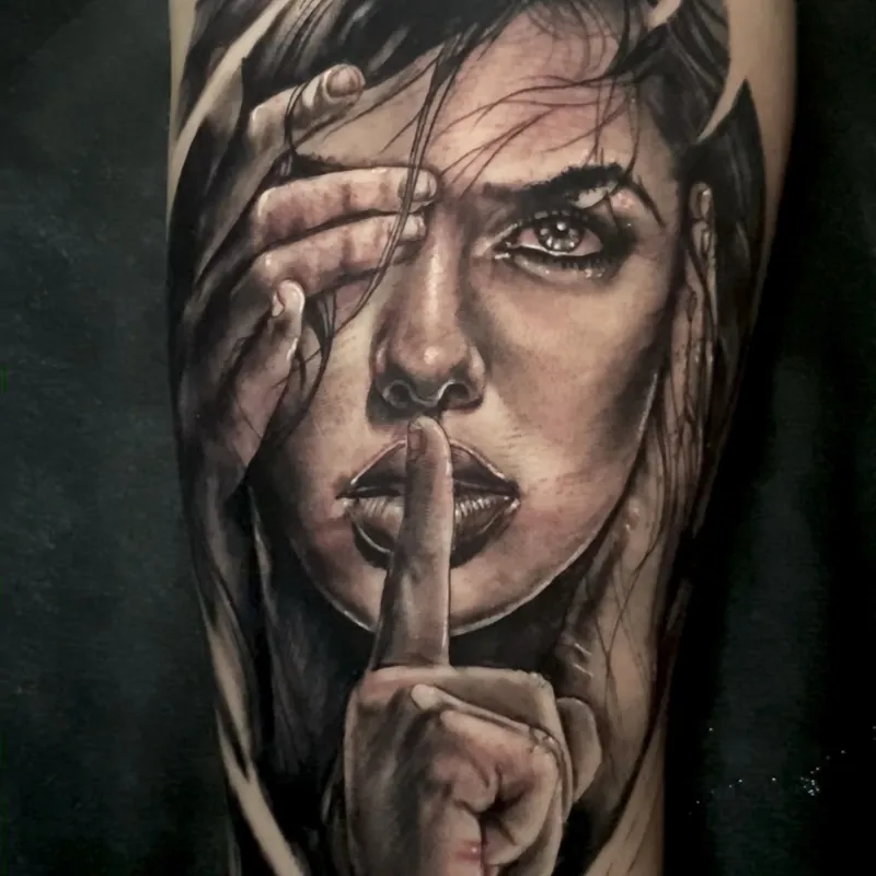 Black and grey realism tattoo of a woman's windblown-hair portrait, one hand near her eye and a finger to her lips, on the forearm.