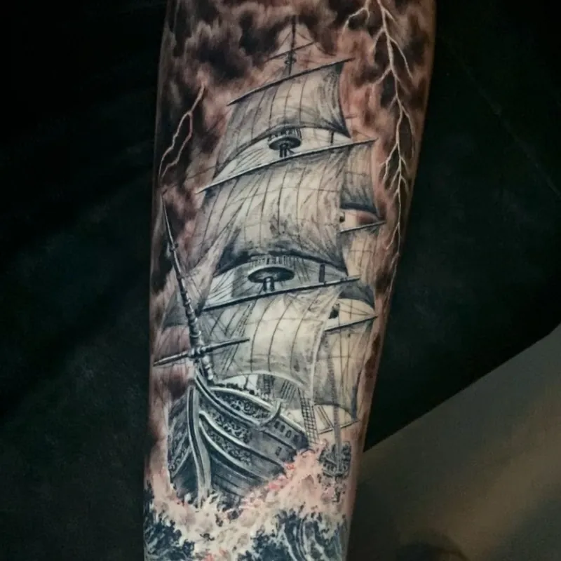 Black and grey realism tattoo of a tall sailing ship under full sail in a storm, with lightning splitting dark clouds above and breaking waves below, on the forearm.