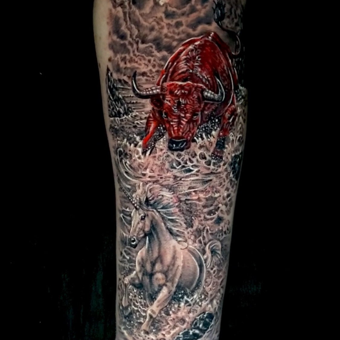 Color realism tattoo of a red bull charging through shallow water with a white horse galloping below it, under heavy storm clouds, on the forearm.