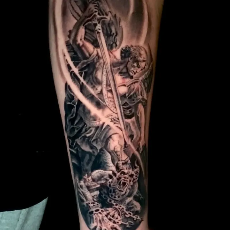 Black and grey realism tattoo of the archangel Michael with spread wings driving a sword down into a horned demon, with a ringed halo behind him, on the forearm.